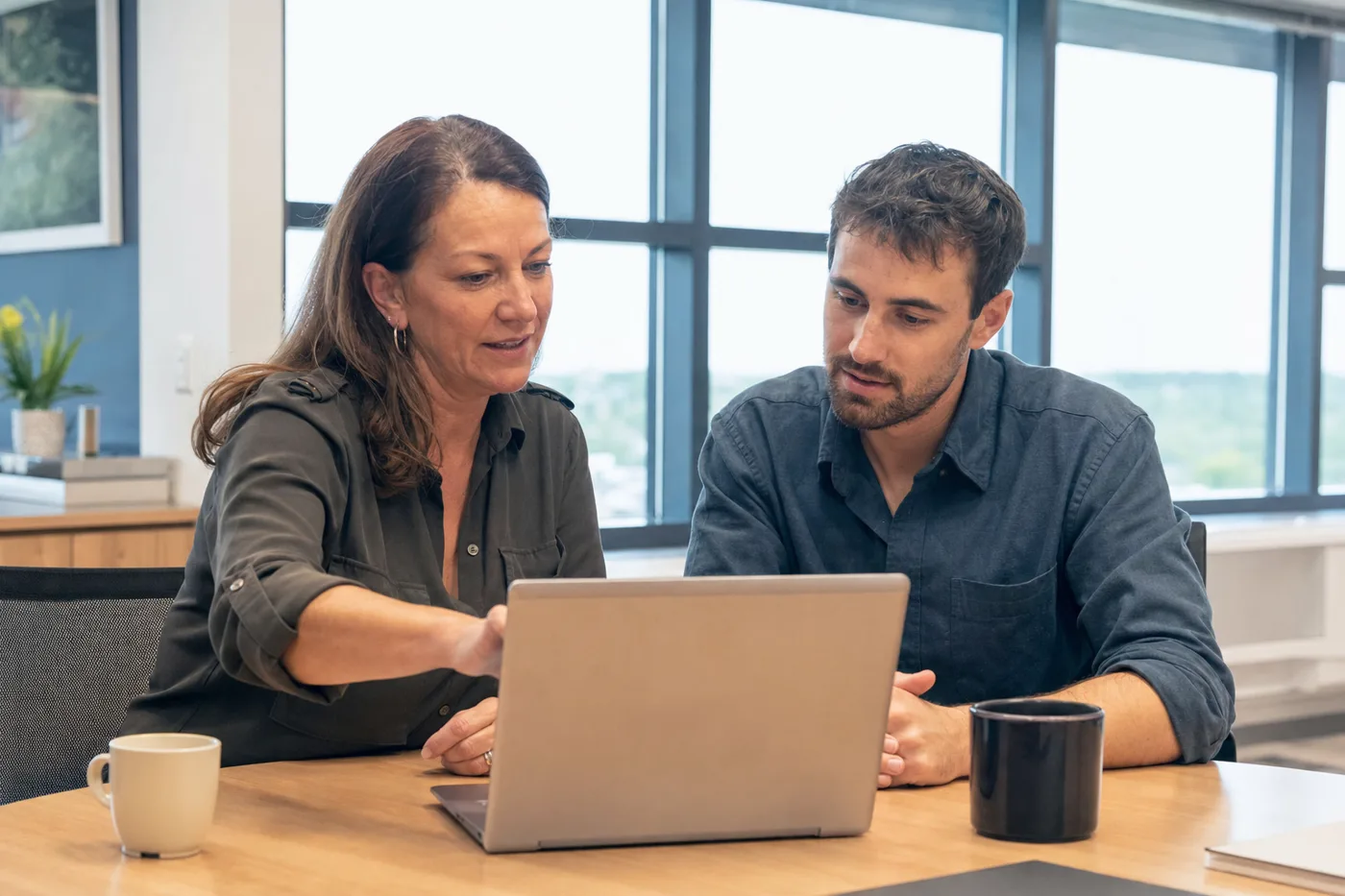 A manager and an employee reviewing practice-session feedback together on a laptop after a coaching exercise