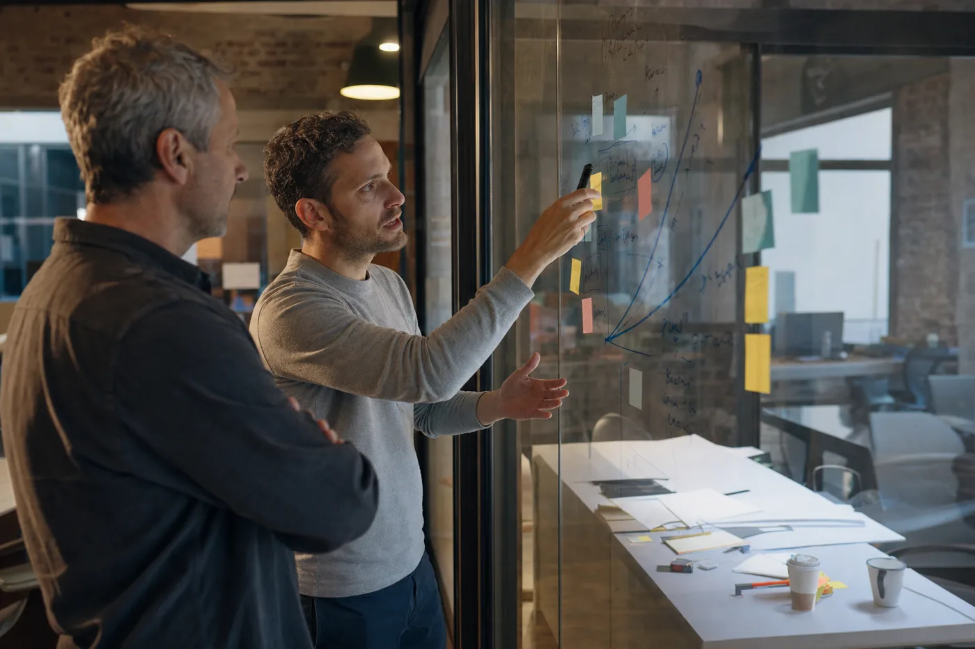 Two coworkers planning how to close the AI skills shortage with internal training at an office whiteboard