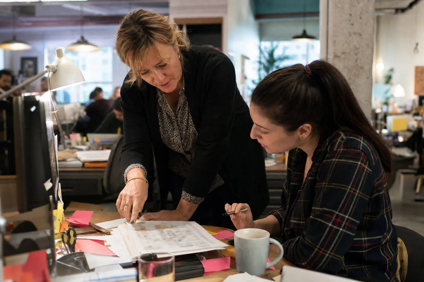 A manager gives a new employee honest corrective feedback at a desk, the human antidote to AI sycophancy in learning