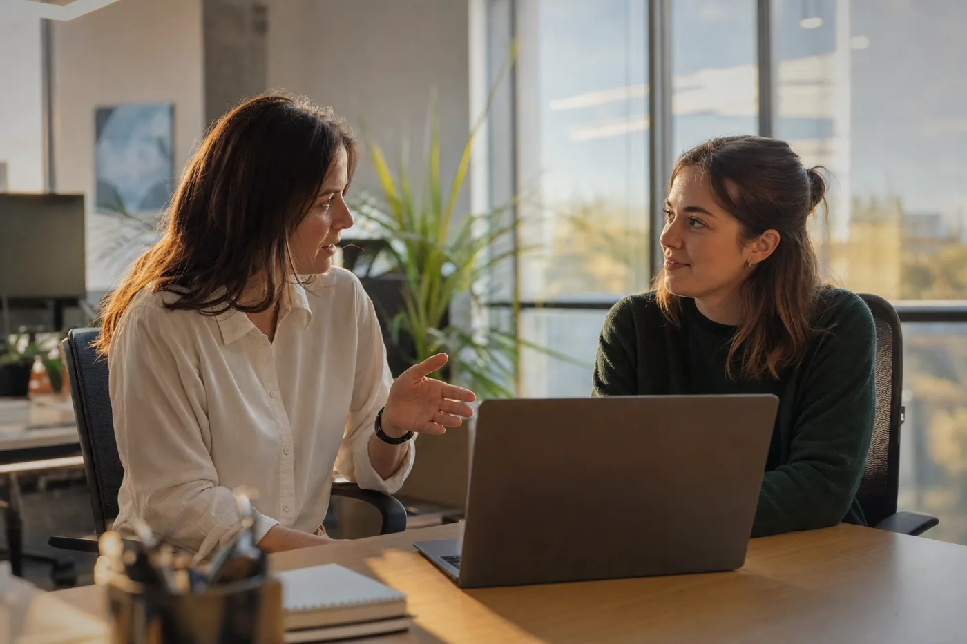 A manager and a new hire talking through a screen together in a bright office, showing the human support that lifts AI tutor engagement
