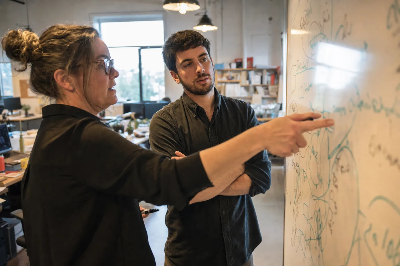 An L&D team running an AI tutoring reality check at a whiteboard covered in hand-drawn learning curves