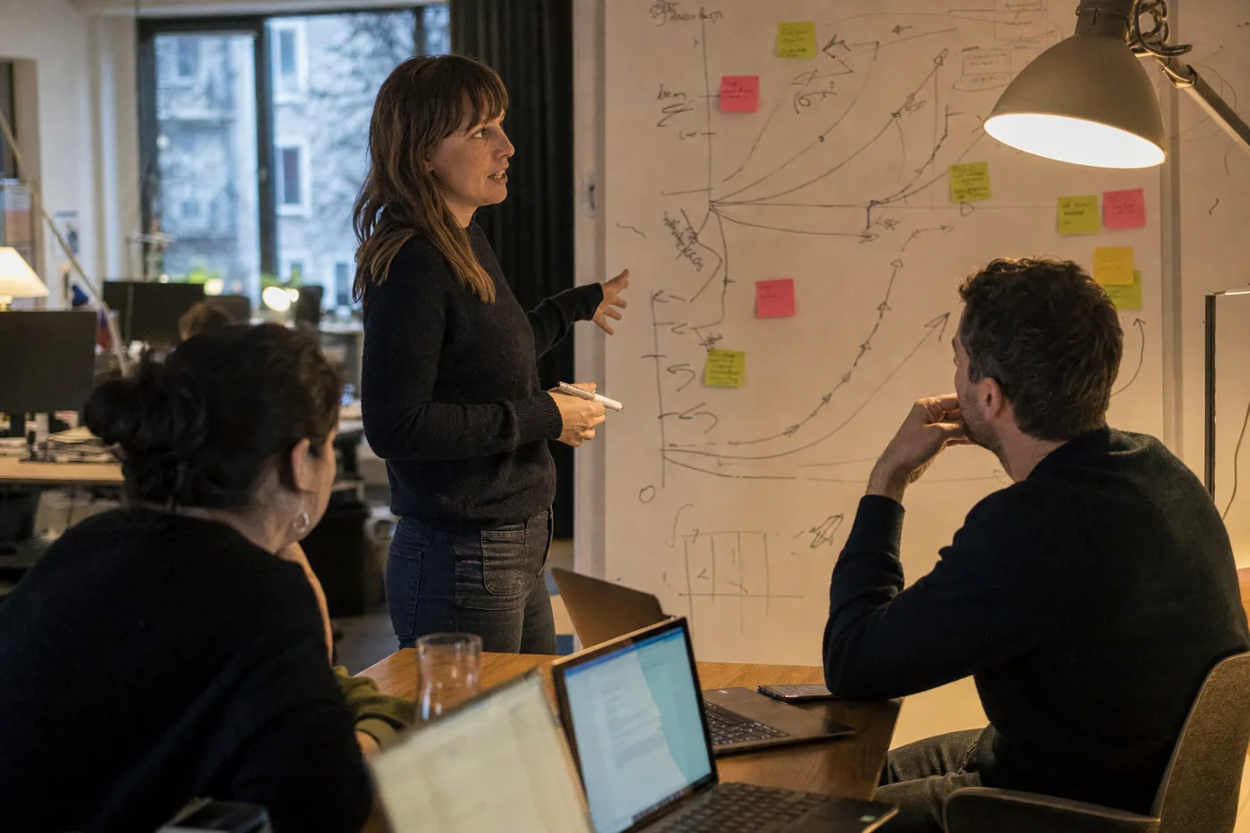 Coworkers in an AI upskilling session working through a hands-on exercise at an office whiteboard