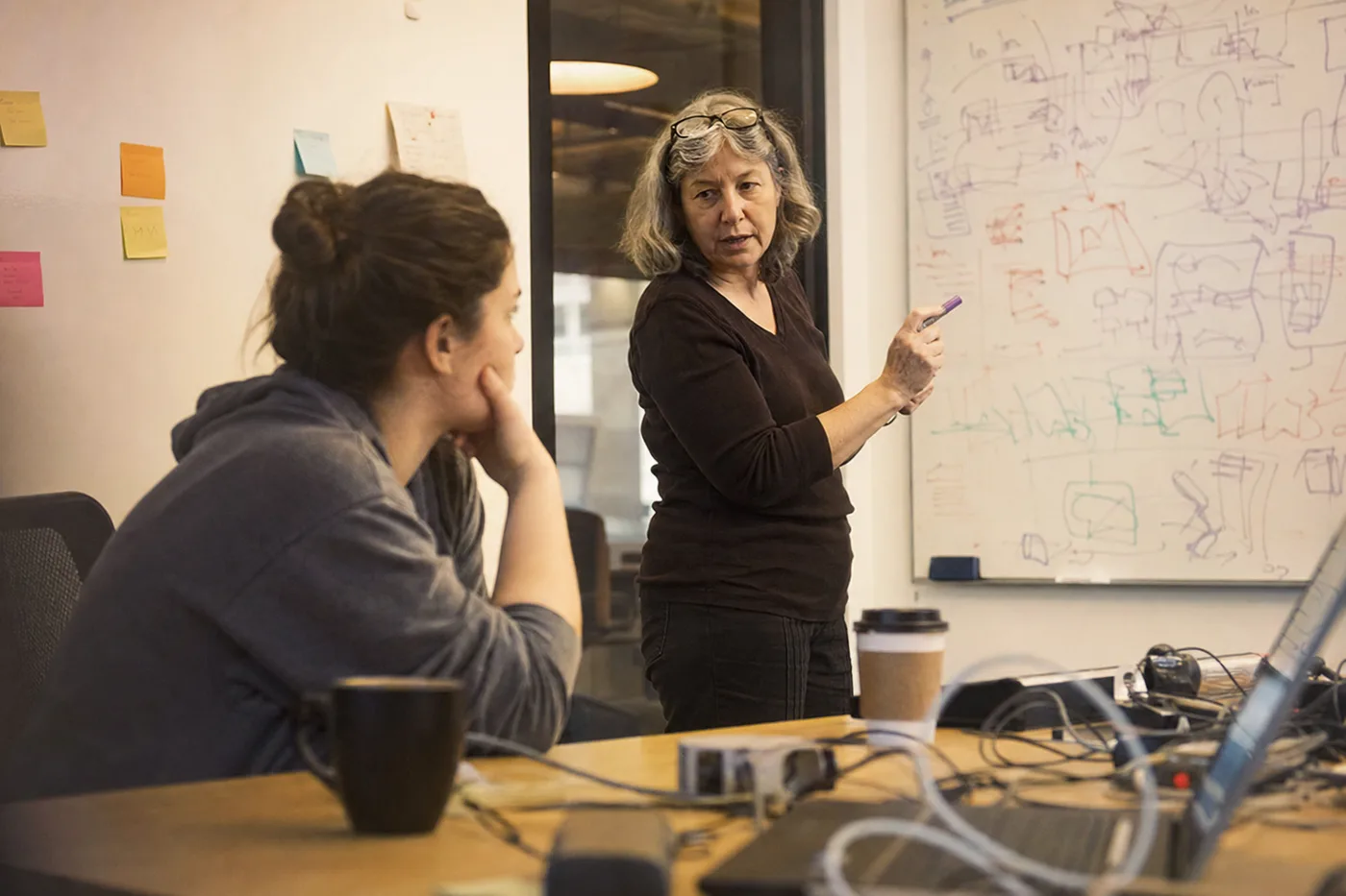 Senior engineer explaining a whiteboard diagram to a puzzled new hire, a classic case of the curse of knowledge in training