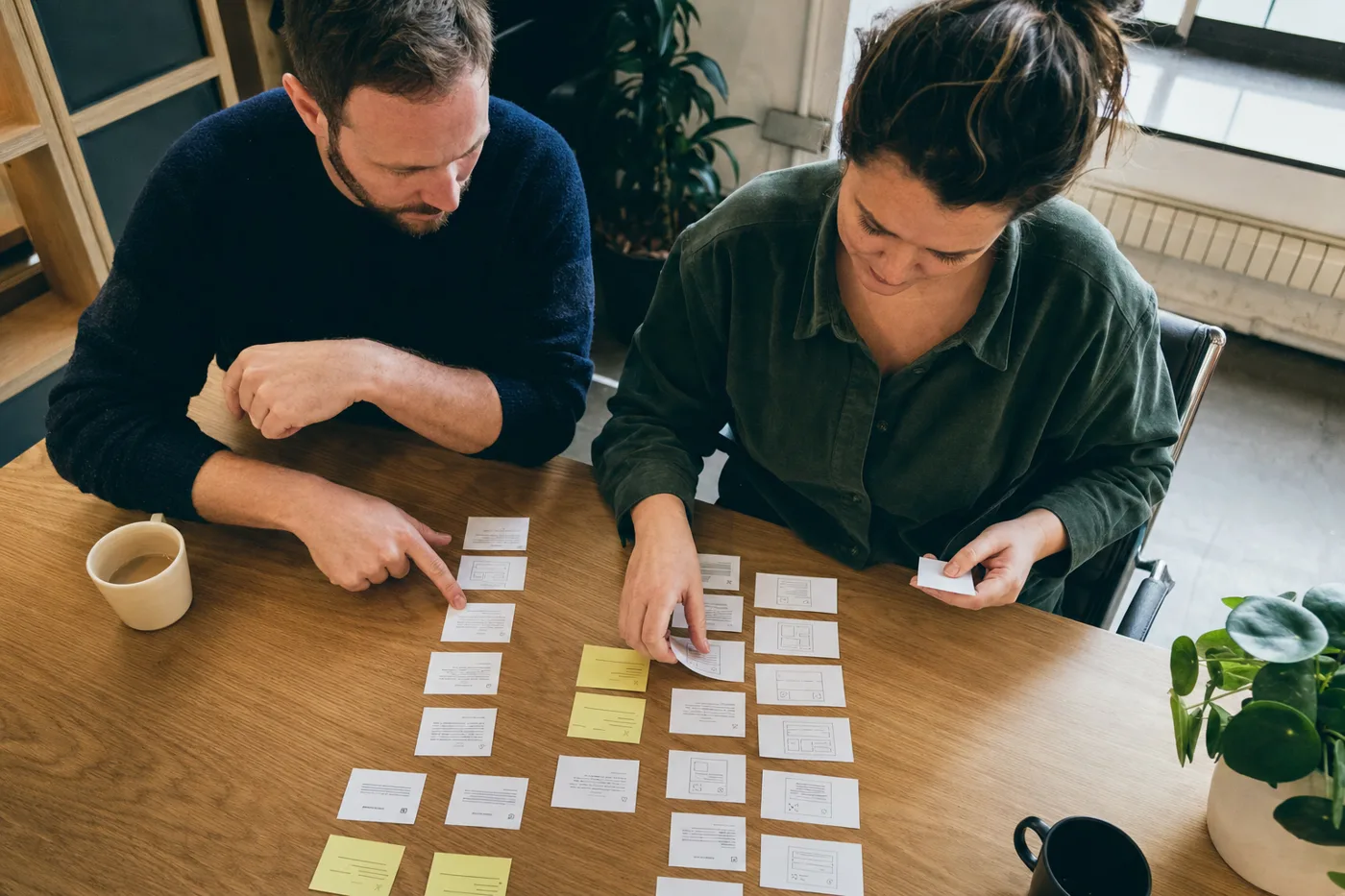 Two coworkers map training concepts on printed cards spread across a desk