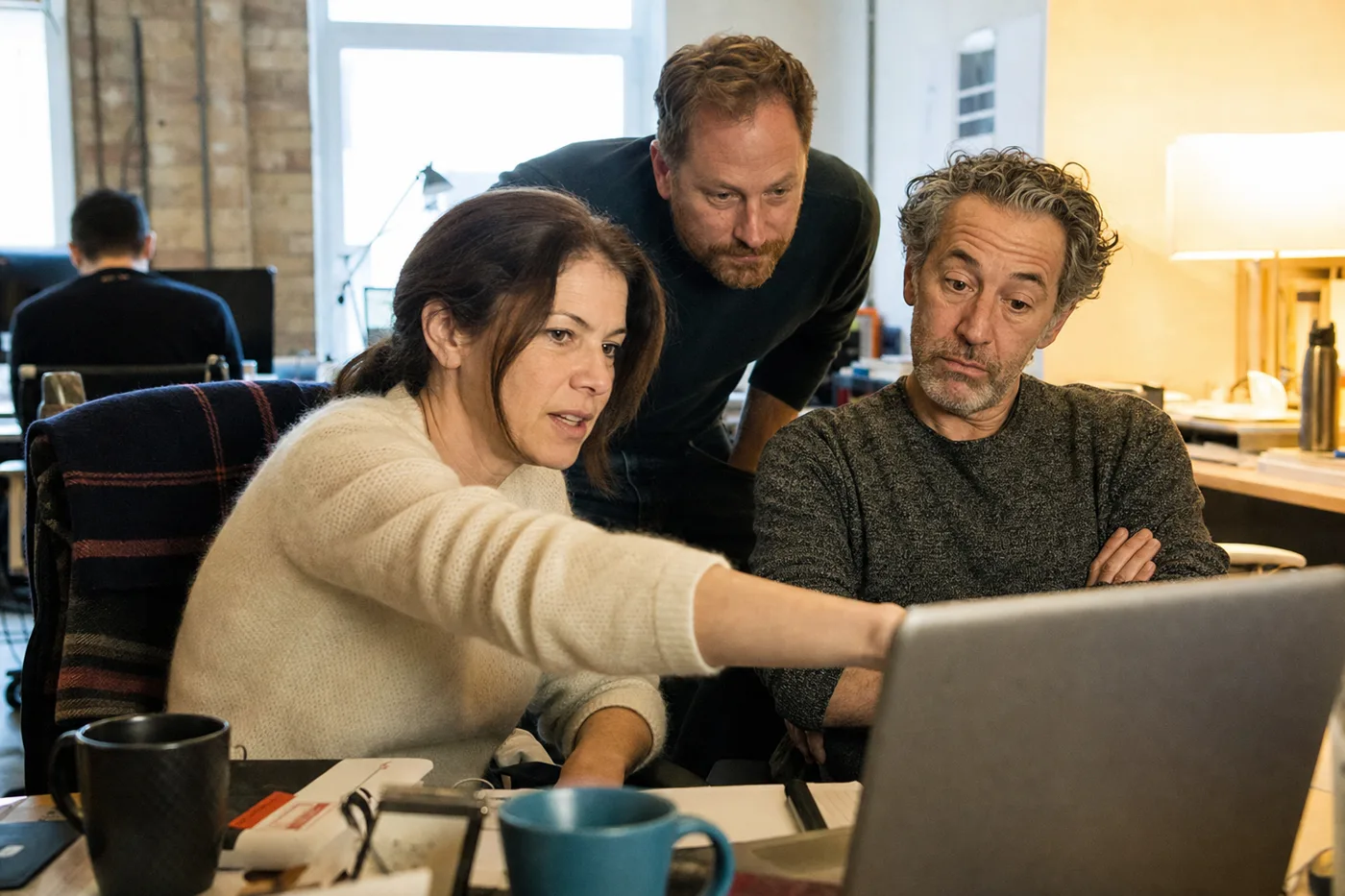 A coworker demonstrates an AI tool on a laptop to a skeptical colleague, the moment employee trust in AI starts to form