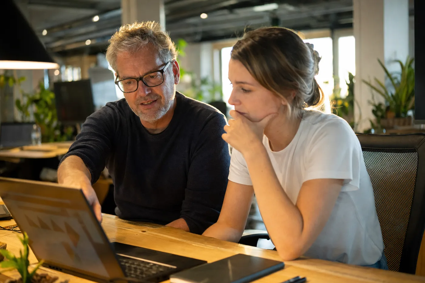 Two coworkers reviewing an enterprise AI tutor rollout together at a shared desk in a bright office