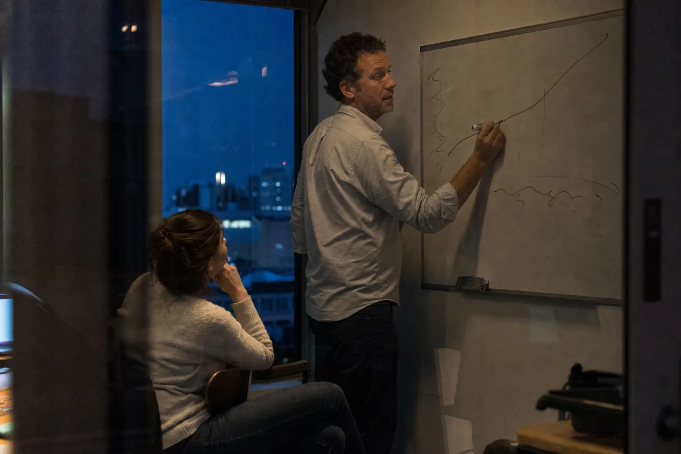 Team lead sketching a learning curve on a whiteboard during an evening coaching session