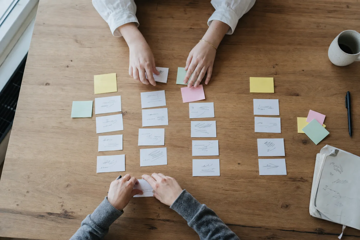 Overhead view of hands sorting printed scenario cards on a desk during a workplace training exercise