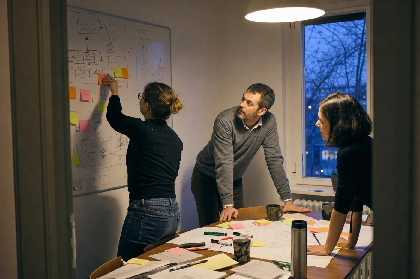 An L&D team plans a new onboarding flow with sticky notes and rough sketches on a whiteboard