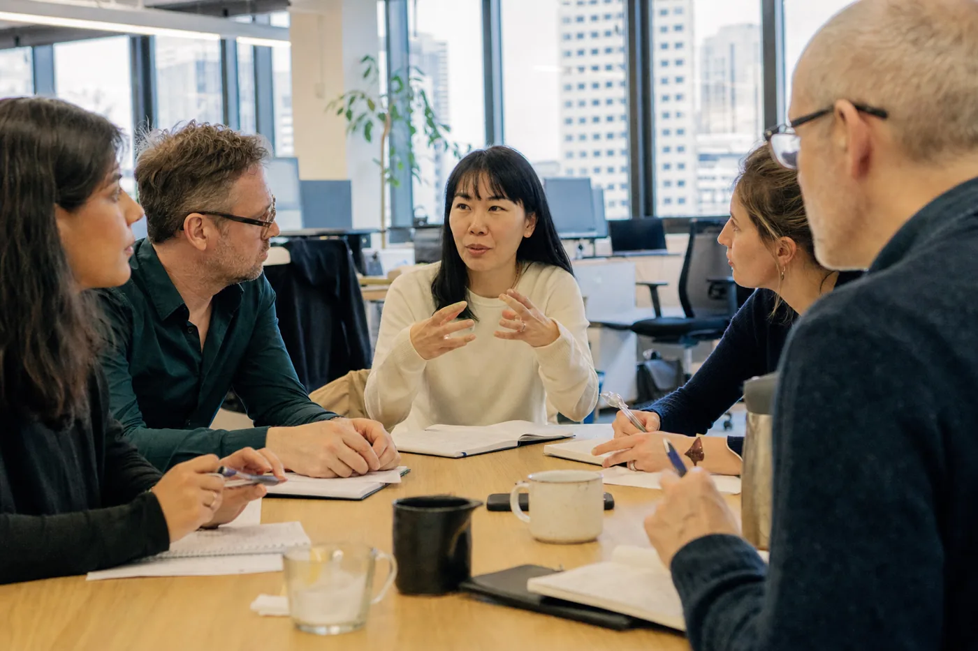 A diverse group of coworkers in a bright office during a multilingual employee training session, learning together around a table