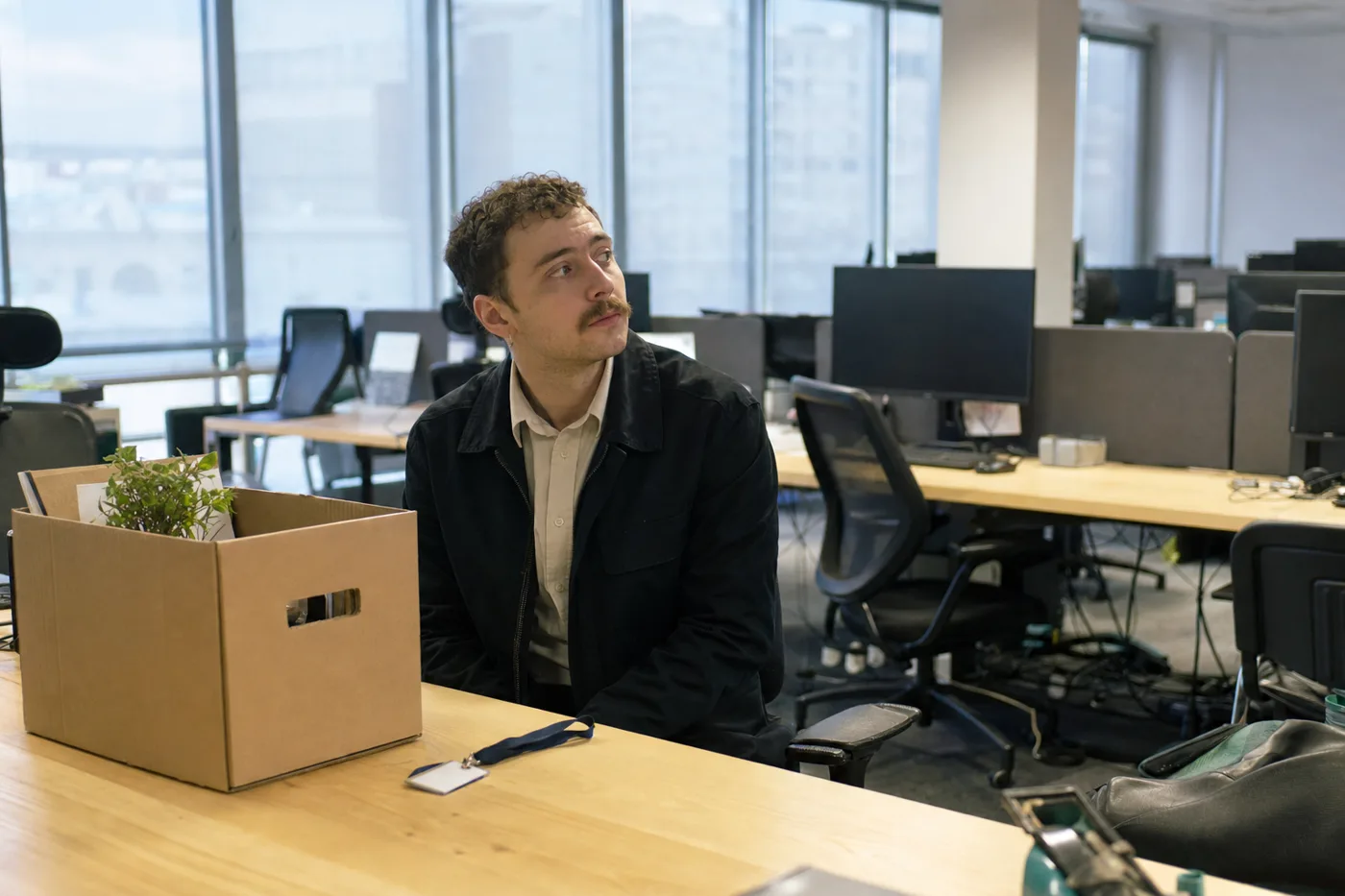 A new employee sitting alone at an empty desk on a quiet first morning in the office