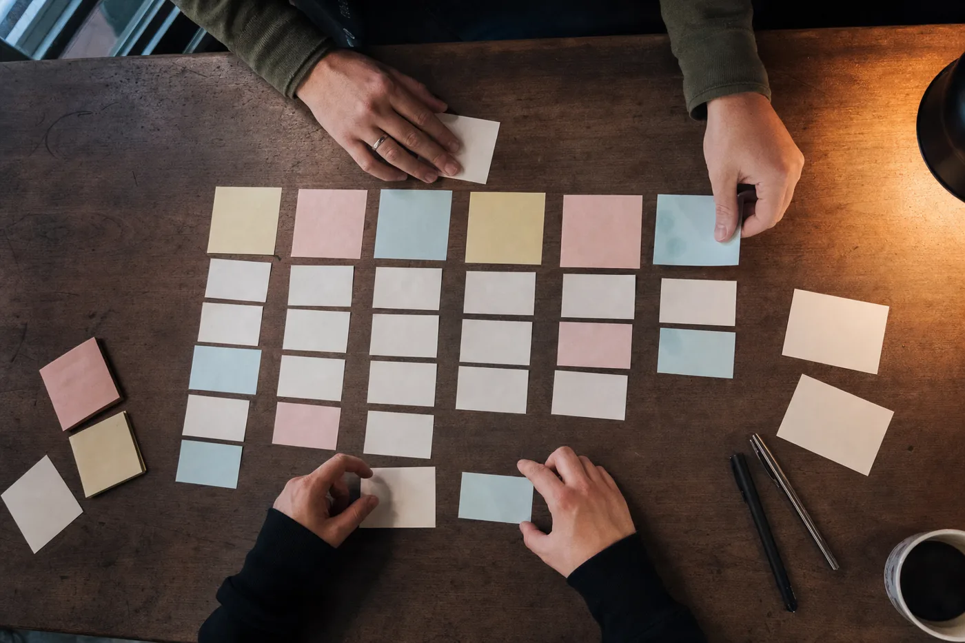 Hands arranging a week-by-week preboarding schedule with printed cards on a desk