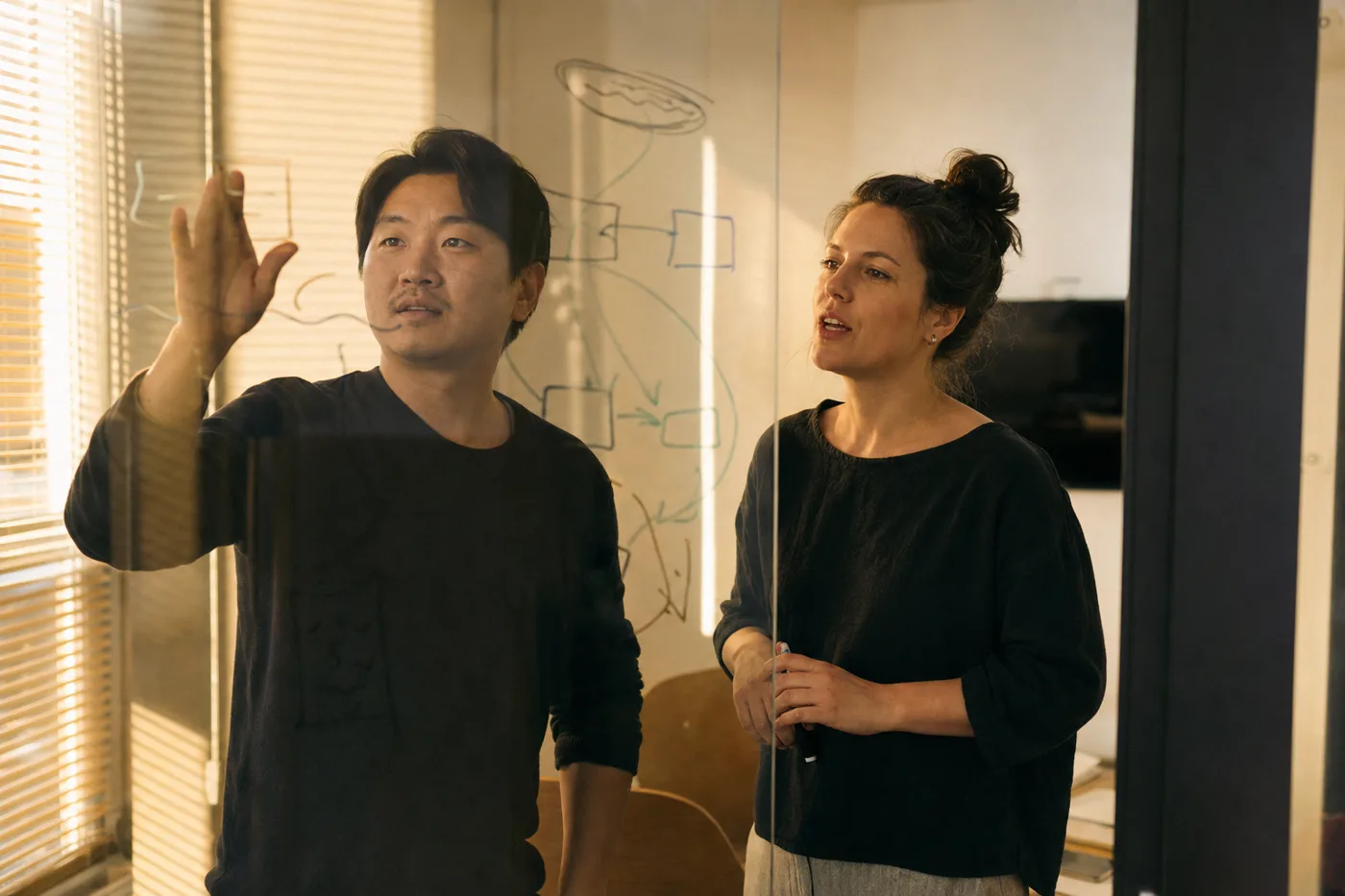 Two coworkers practicing a verification scenario together at a glass wall during golden hour