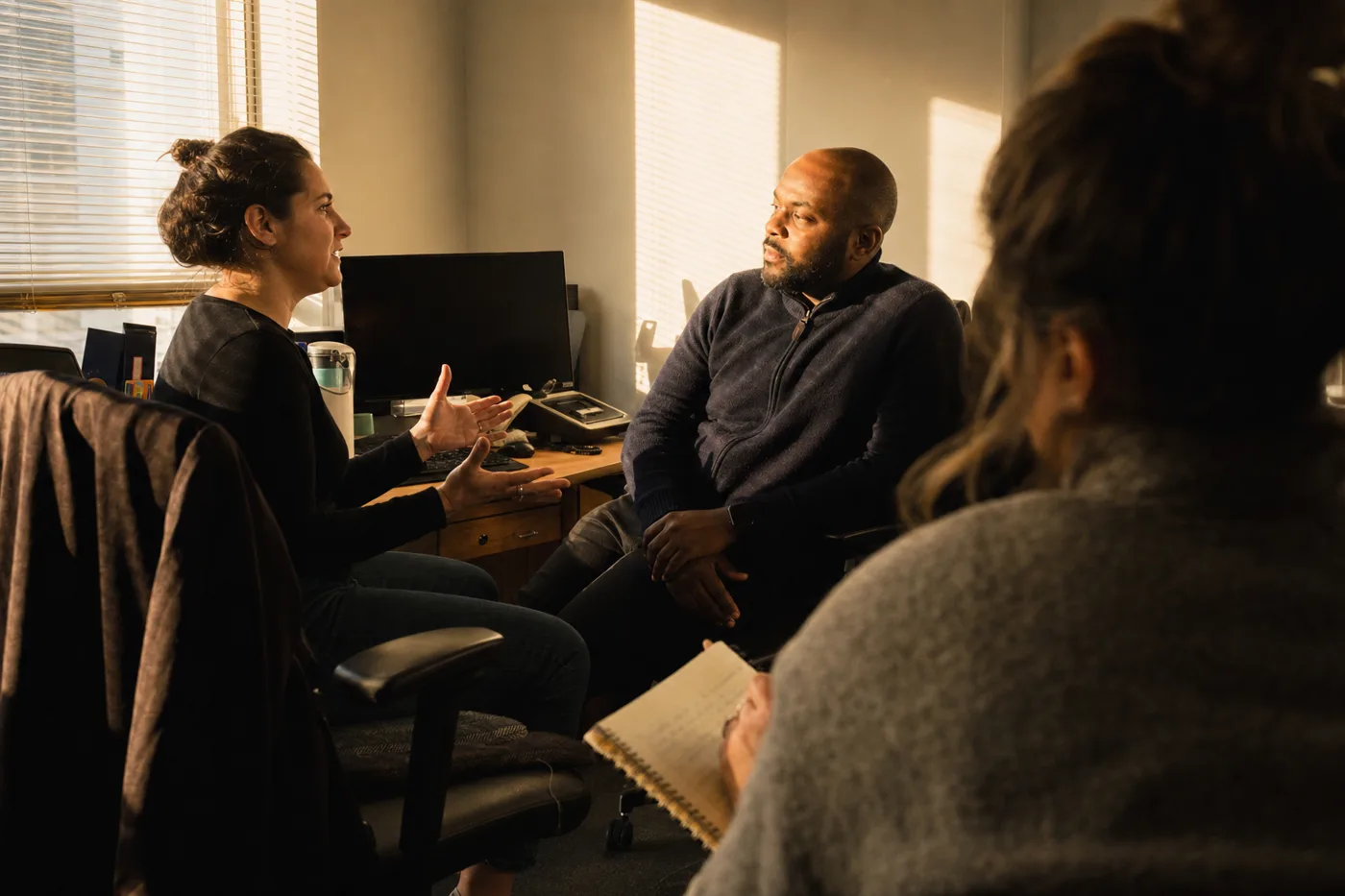 Two colleagues rehearse a feedback conversation while a facilitator observes during a practice session