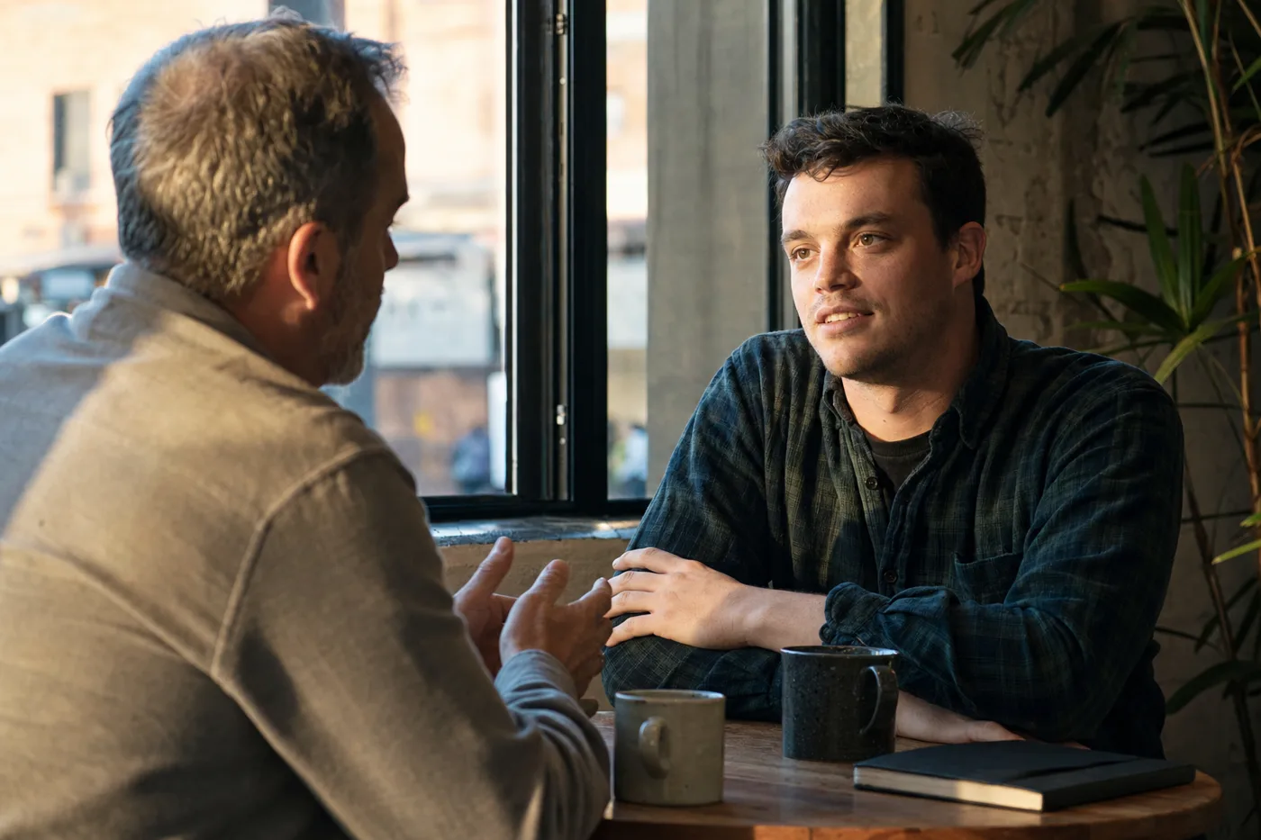 Manager and new employee having a one-on-one conversation by a window in warm afternoon light